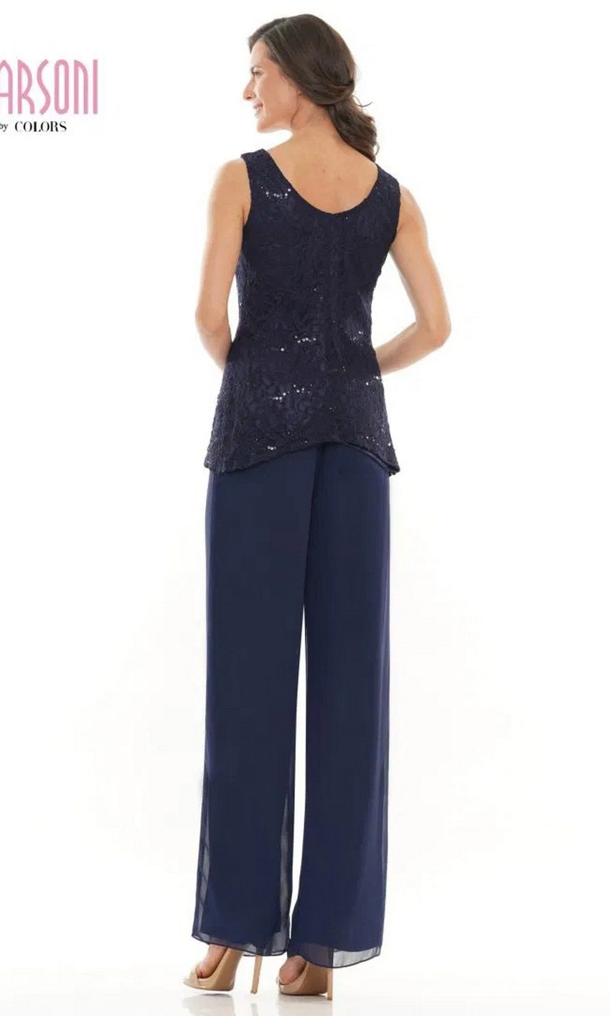 A woman stands facing away, wearing the Marsoni M303 Long Formal Pantsuit in navy blue lace with wide-leg pants and beige high heels.